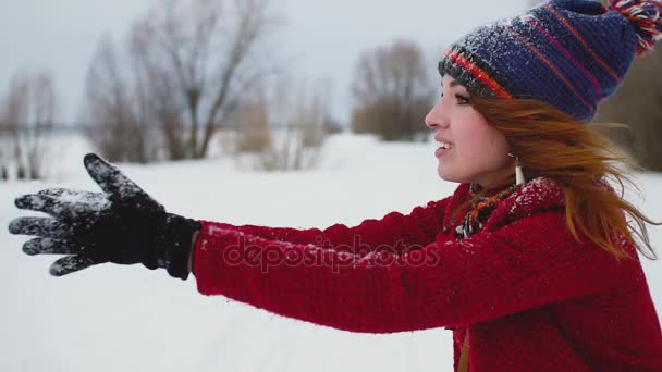 Genç Kızıl saçlı kadının kar yağışı açık havada, gülümseyen ve kamera yavaş hareket 120 fps bakarak gülmek — Stok video