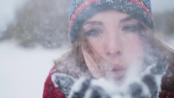 Красная голова молодой женщины раздувает снег в камере в сверхмедленном режиме 120 кадров в секунду — стоковое видео