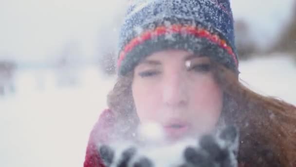 Piękna czerwona głowa młoda kobieta jest dmuchanie śniegu w aparacie w super zwolnionym tempie 120fps — Wideo stockowe