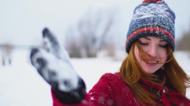 Молодая счастливая красивая рыжая женщина веселится со снегом в перчатках в замедленной съемке — стоковое видео