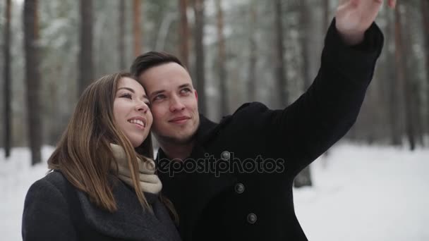 Férfi téli erdőben barátnőjével beszél mutat valamit, ezen a környéken: és — Stock videók