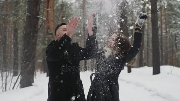 20 代若いカップルが後ろに投げる雪と冬の森で楽しい時を過す — ストック動画