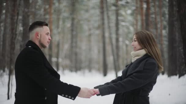 20s Man está levantando sua namorada e se divertindo em uma floresta de inverno de neve — Vídeo de Stock