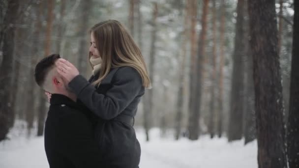 20s Man está levantando sua namorada e se divertindo em uma floresta de inverno de neve — Vídeo de Stock