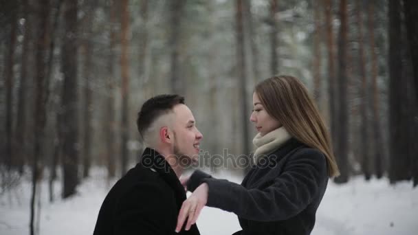 20s Man está levantando sua namorada e se divertindo em uma floresta de inverno de neve — Vídeo de Stock
