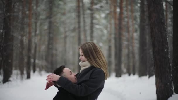 20s El hombre está levantando a su novia y divertirse en un bosque de invierno de nieve — Vídeo de stock