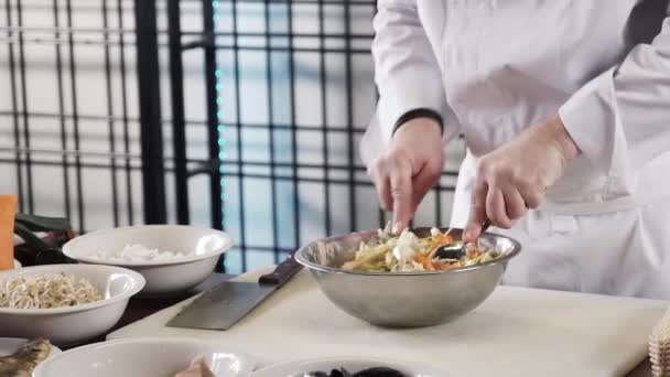 混合沙拉碗由厨师在现代高等学校内部厨房里的手的特写 — 图库视频影像