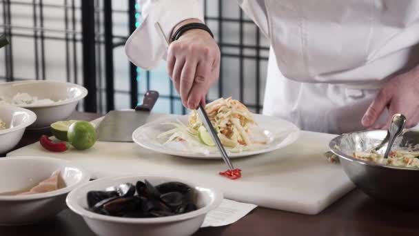 Chef cuisinier décorer salade asiatique avec de la saucisse sur une table en bois au ralenti — Video
