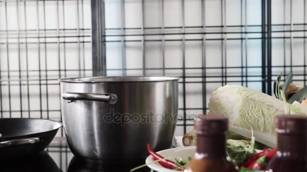 Kokande kastrull på brännaren bland grönsaker — Stockvideo