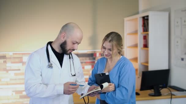 30s chauve médecin uscuss avec 20s blonde infirmière en uniforme médical au bureau 4k — Video