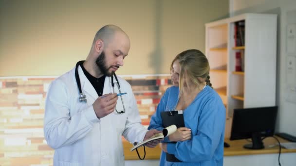 30s chauve médecin uscuss avec 20s blonde infirmière en uniforme médical au bureau 4k — Video