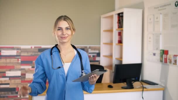 Young 20s female nurse in blue is thumbs up and wink at medical office — Stock Video