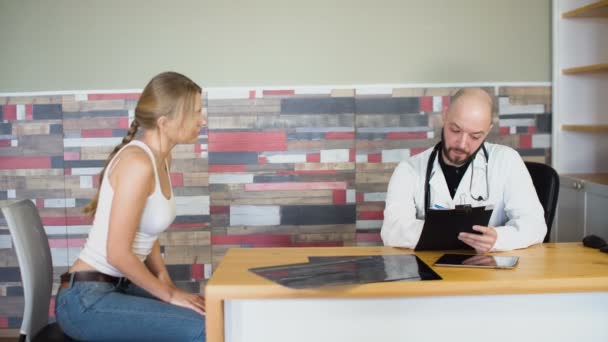 Volwassen professionele arts bespreken met vrouwelijke vrouw patiënt bij medische kamer kantoor met tablet 4k — Stockvideo