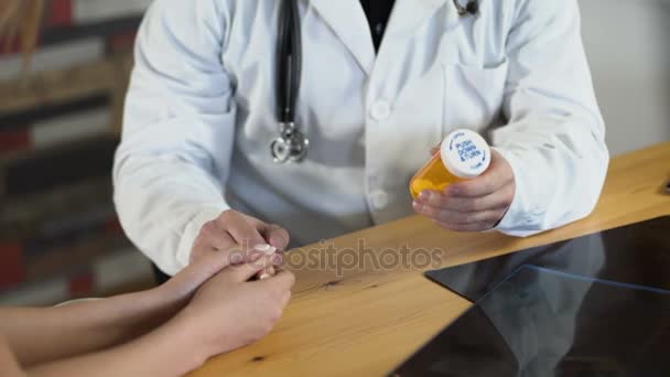 Close up hands dostor gives a pills in a orange jar to female patient — Stock Video