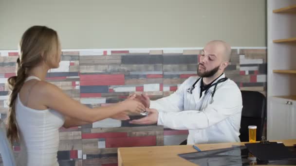 30'lu sakallı doktor yapmak onun elini sıkmak ve ona 4 k sakin jest kadın kız hastanın el tıbbi göreve cesaret — Stok video