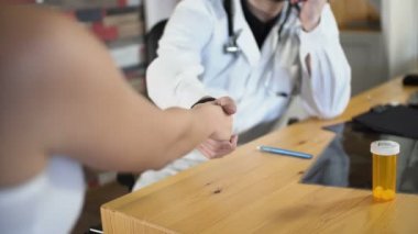 Doktor ve hasta tıbbi oda ofis ahşap masa 4 k üzerinde tokalaşırken yakın çekim