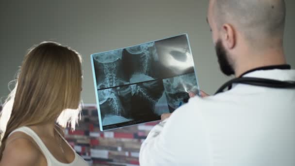 Лысый взрослый 30-летний доктор показывает рентген пациенту и обсуждает это — стоковое видео