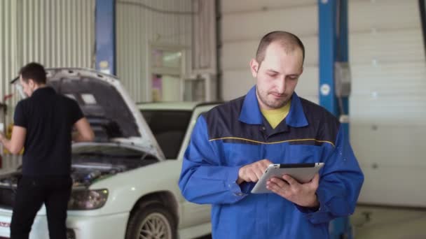 Auto monteur met scherm van de aanraking van de Tablet PC op een auto cepair service — Stockvideo