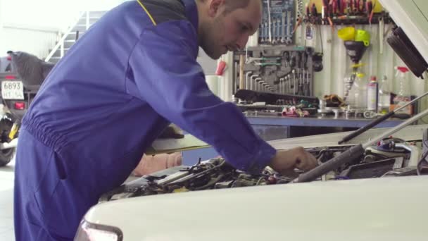 Automechaniker in blauer Uniform fixiert Auto unter geöffneter Motorhaube, Diagnose — Stockvideo