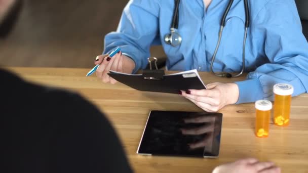Молодая женщина-врач дает таблетки и наркотики в оранжевой банке. close up on wooden table 4k — стоковое видео
