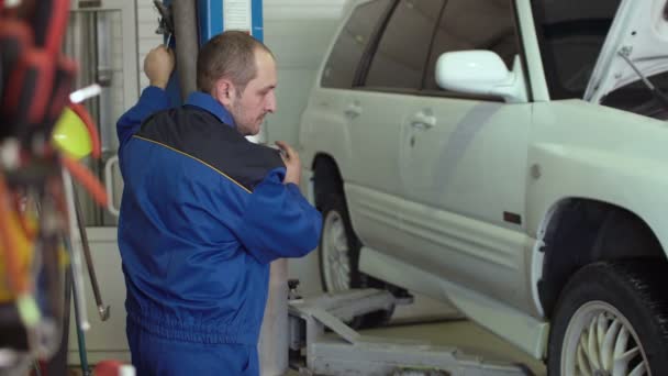 40s carro mecânico levantamento branco crossover no carro reparação estação de auto serviço — Vídeo de Stock