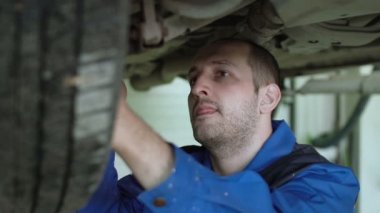 Araba tamircisi araba araba tamircisi mavi tulum arabaya kaldırdı crossover uzaklaştırılmış kontrol ediyor