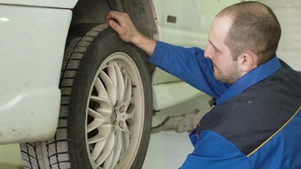 Mecánico del coche está comprobando las ruedas del coche en crossover en el servicio de reparación del coche — Vídeos de Stock