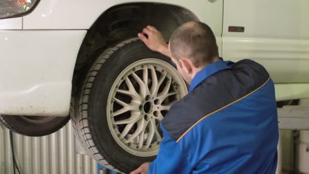 Mecánico del coche está comprobando las ruedas del coche en crossover en el servicio de reparación del coche — Vídeo de stock