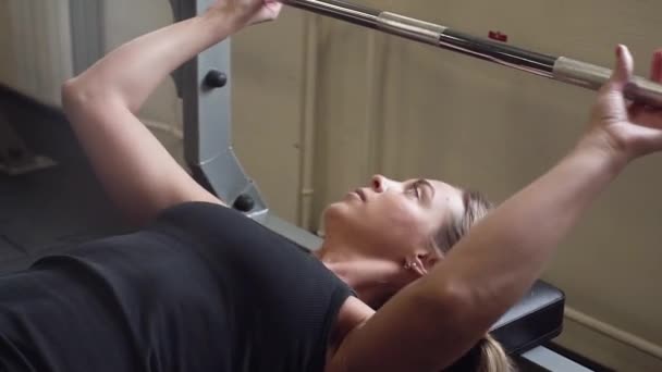 20s femme athlétique en noir sportswear soulève haltère dans une salle de gym — Video