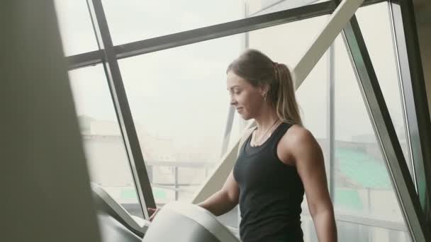 Woman is tune change mode of Treadmill before training in a gym behind a window — Stock Video