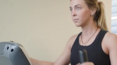 güzel 20'li yaşlarda bir spor salonunda elips makine üzerinde çalışan spor giyim kadın