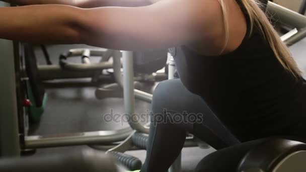 20s schoonheid sportieve vrouw doen oefeningen op een machine in een sportschool — Stockvideo