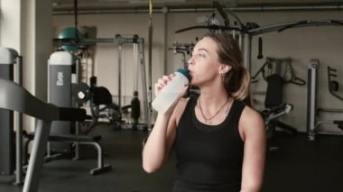 Bir sporcumuz portresi ile sportif şişe içecek sudur. arka plan makinelerde spor salonu
