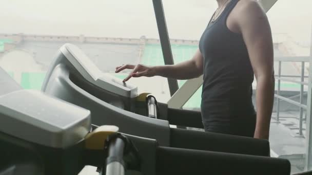 Η γυναίκα είναι μελωδία αλλαγή λειτουργίας της Treadmill πριν την προπόνηση στο γυμναστήριο πίσω από ένα παράθυρο — Αρχείο Βίντεο