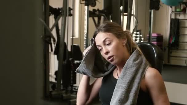 Trött sportiga idrottskvinna torkar pannan med en handduk medan sittande och svårt att andas — Stockvideo