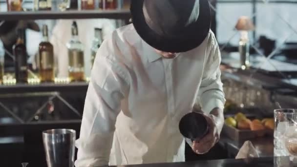 Professioneller Barkeeper mit schwarzem Hut macht Cocktail in einer Bar — Stockvideo