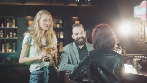 Perusahaan dari 3 orang muda 20-an teman sedang bersenang-senang berbicara di bar malam, pub — Stok Video