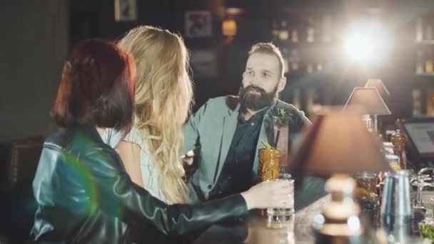 Empresa de 1 hombre 2 mujeres son gafas de clink en el bar, feliz hablando y riendo — Vídeo de stock