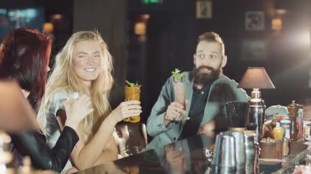 Компания из 1 мужчины 2 женщины звонят стаканы в баре, счастливы говорить и смеяться — стоковое видео
