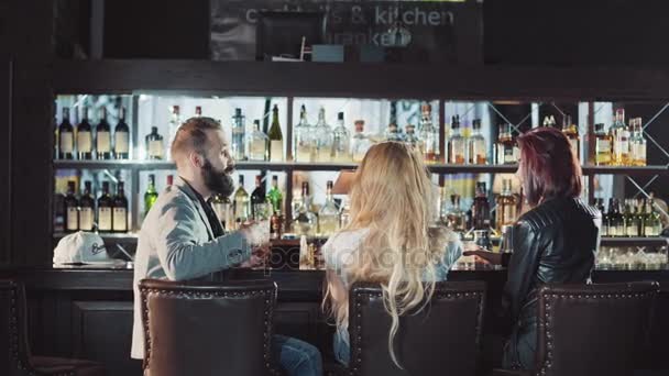 Companhia de 3 amigos positivos felizes comemorando no bar da noite, copos de clink e diversão conversando juntos — Vídeo de Stock