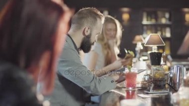 20'li yaşlarda sakallı adam kişidir içki tezgahın menüsüyle oturuyor kokteyl