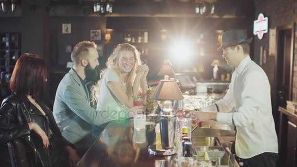 Företaget av 20s vänner är dring cocktails medan bartender i hatt förbereder drycker bakom baren part natt — Stockvideo