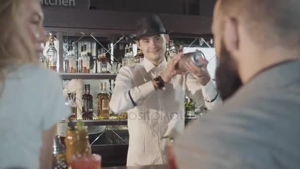 20s bartender is preparing cocktail with shaker behind guests — Stock Video