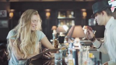 Sarışın 20'li yaşlarda kadın barmen yardımcı olun bir seçim menüde bar