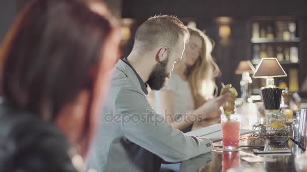 Homem hipster barbudo 20s está flertando com a menina loira em um bar noturno — Vídeo de Stock