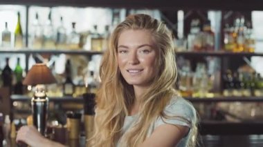 Abiye yakınındaki tezgahın oturuyor ve kameraya bakarak güzel sarışın kadın