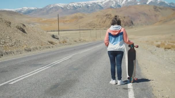 20 代魅力的なツーリストの女性が山の道でロングボードと一緒に — ストック動画