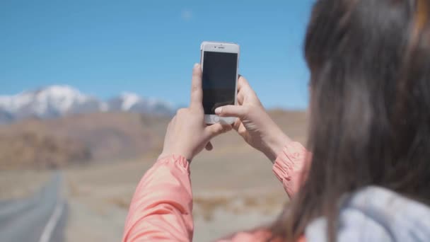 Synvinkel händerna på 20s kvinna är att ta bilder på smarta mobiltelefon med ice toppar och vägen på backgroung — Stockvideo
