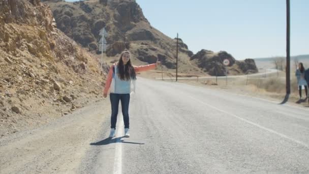 美 20 多岁的女人在沙漠中的盘山公路上搭便车一辆车 — 图库视频影像