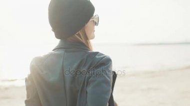 Genç çekici sarışın siyah şapka, deri ceket ve bir şişe bira eller yakın çekim gün batımında dans güneş gözlüğü.